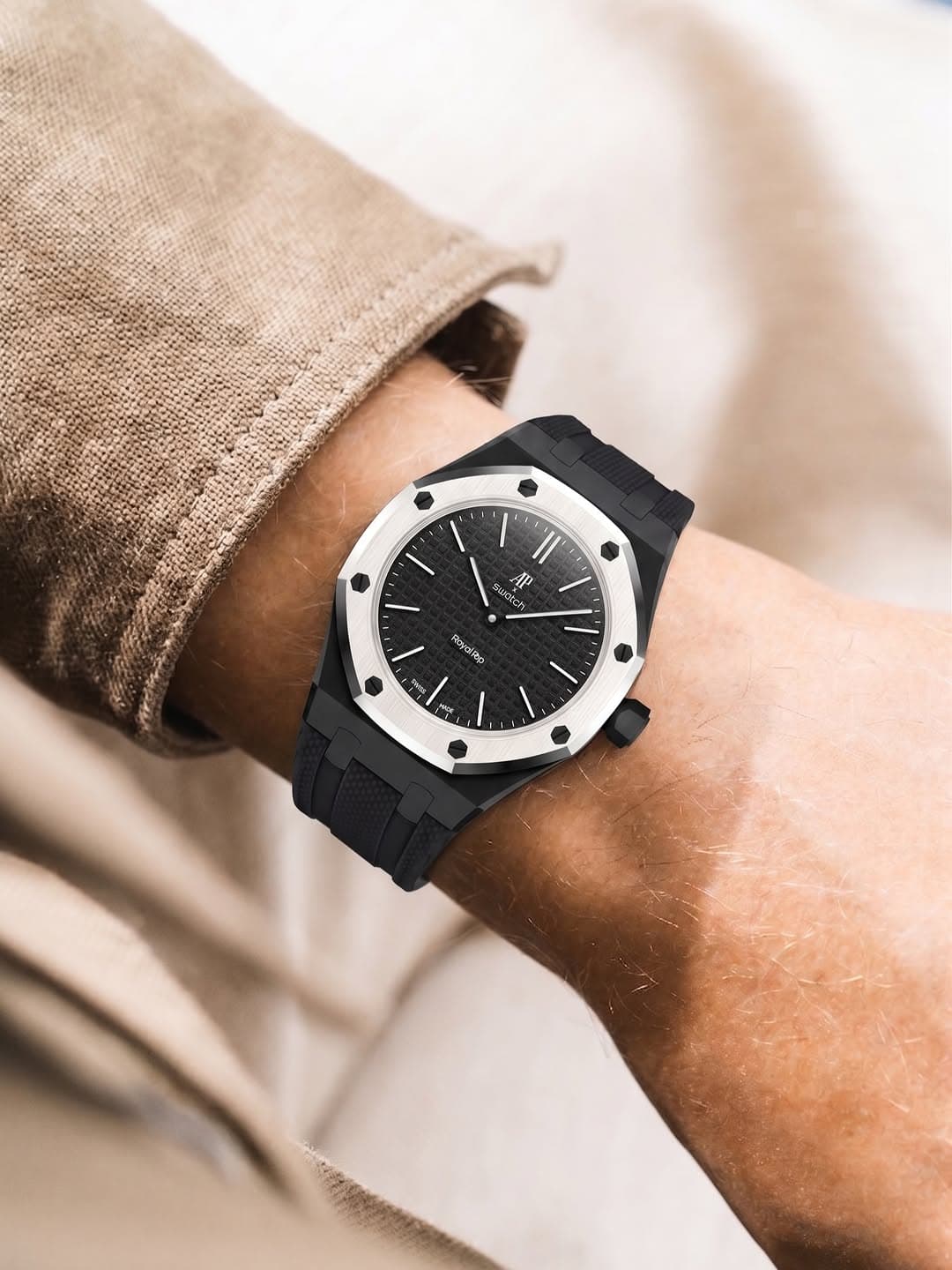 Onyx black silicone strap on the AP × Swatch Royal Pop, on the wrist with a sandstone-colored shirt cuff.